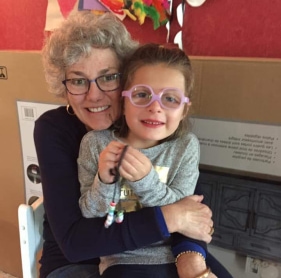 Image of woman embracing child with glasses