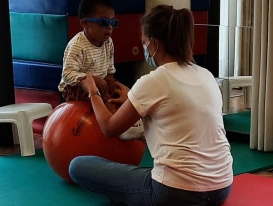 Image of child sitting on ball with teacher